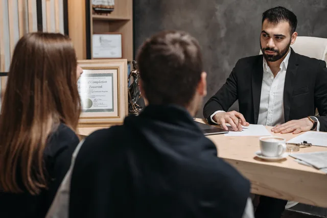 A lawyer in an elegant office meeting with clients, discussing documents. Vetting a startup funding vendor for identity, permissions, fees and continuity