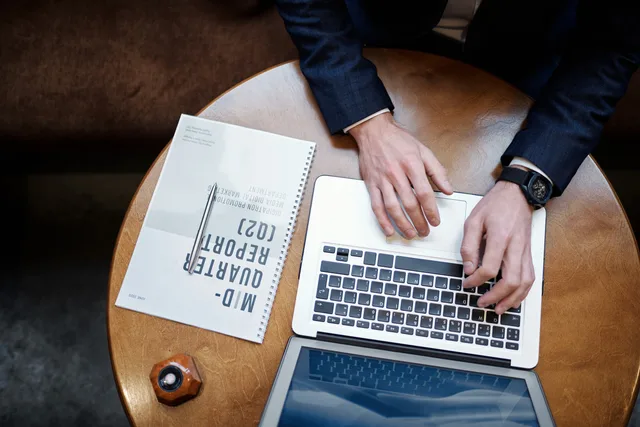 Top view of a businessman typing on a laptop next to a quarterly report on a wooden table. What do UK venture capital firms ask in due diligence?